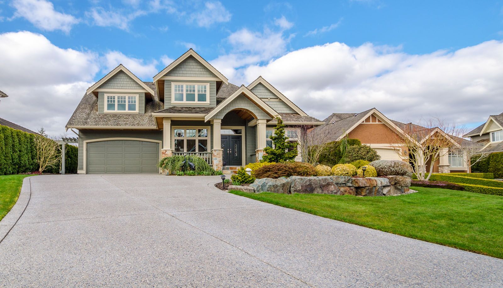 A landscaped home with traditional residential garage doors